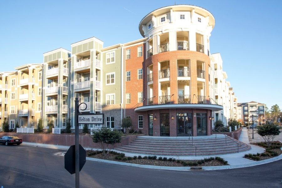 Apartment building with multi-colored facade and circular tower entrance on a sunny day at Town Center at Lake Carolina in Columbia, SC.