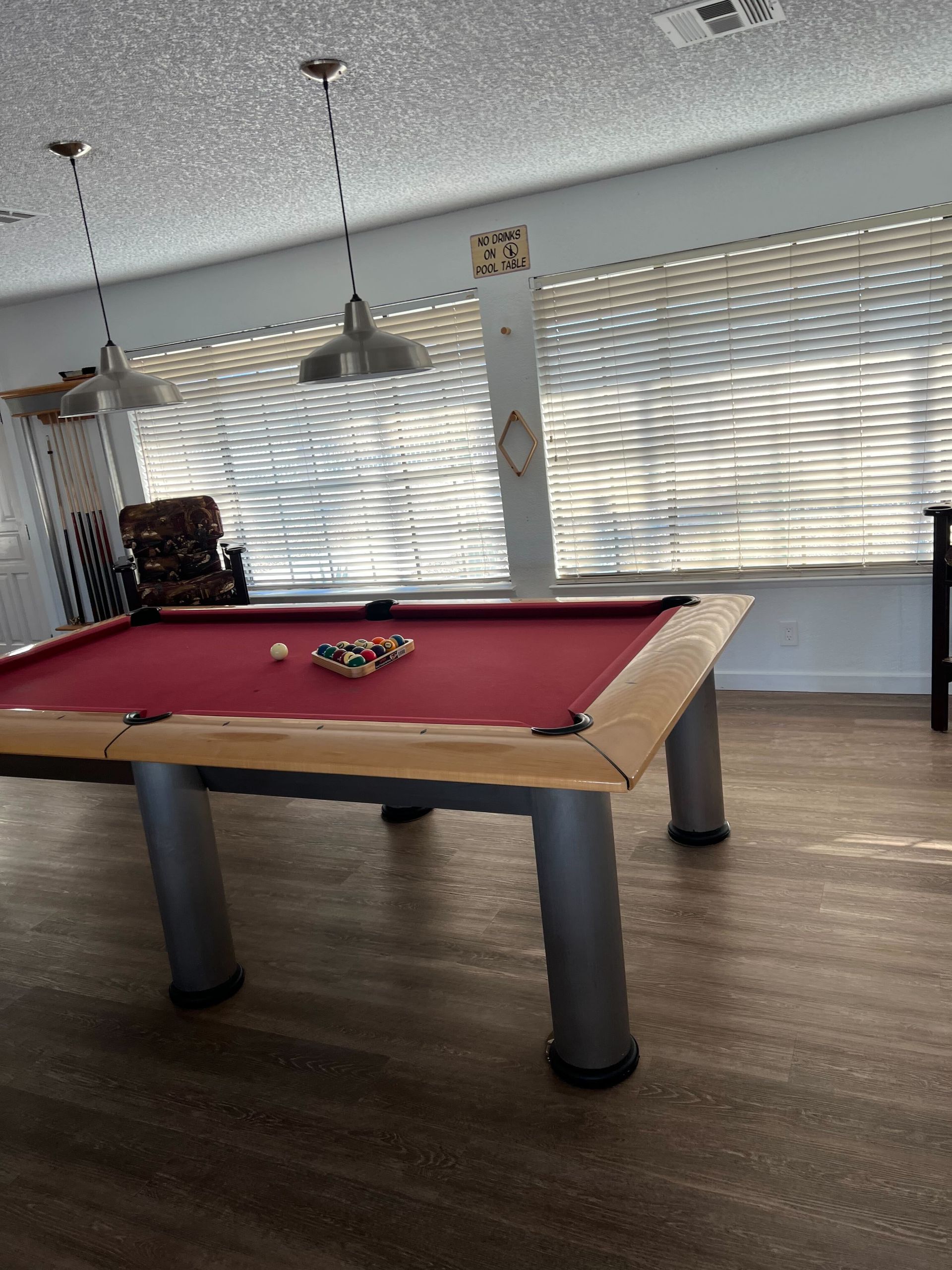 A pool table in a room with blinds on the windows