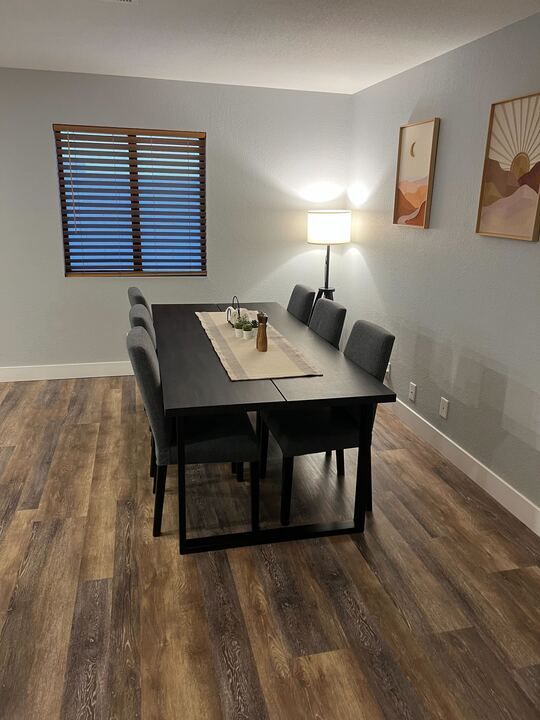 A dining room with a table and chairs and a window.