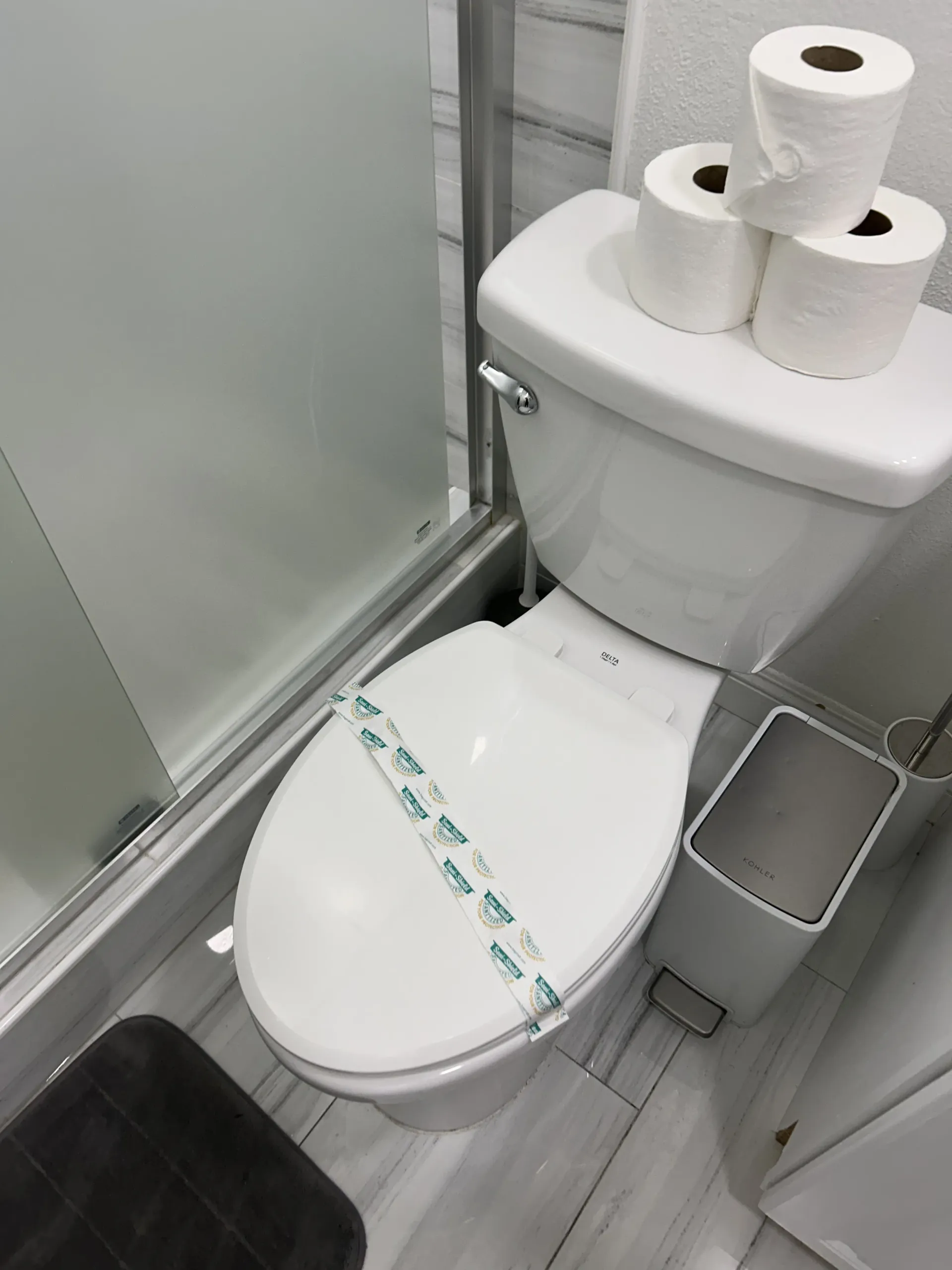 Clean, lined trash bin near the toilet