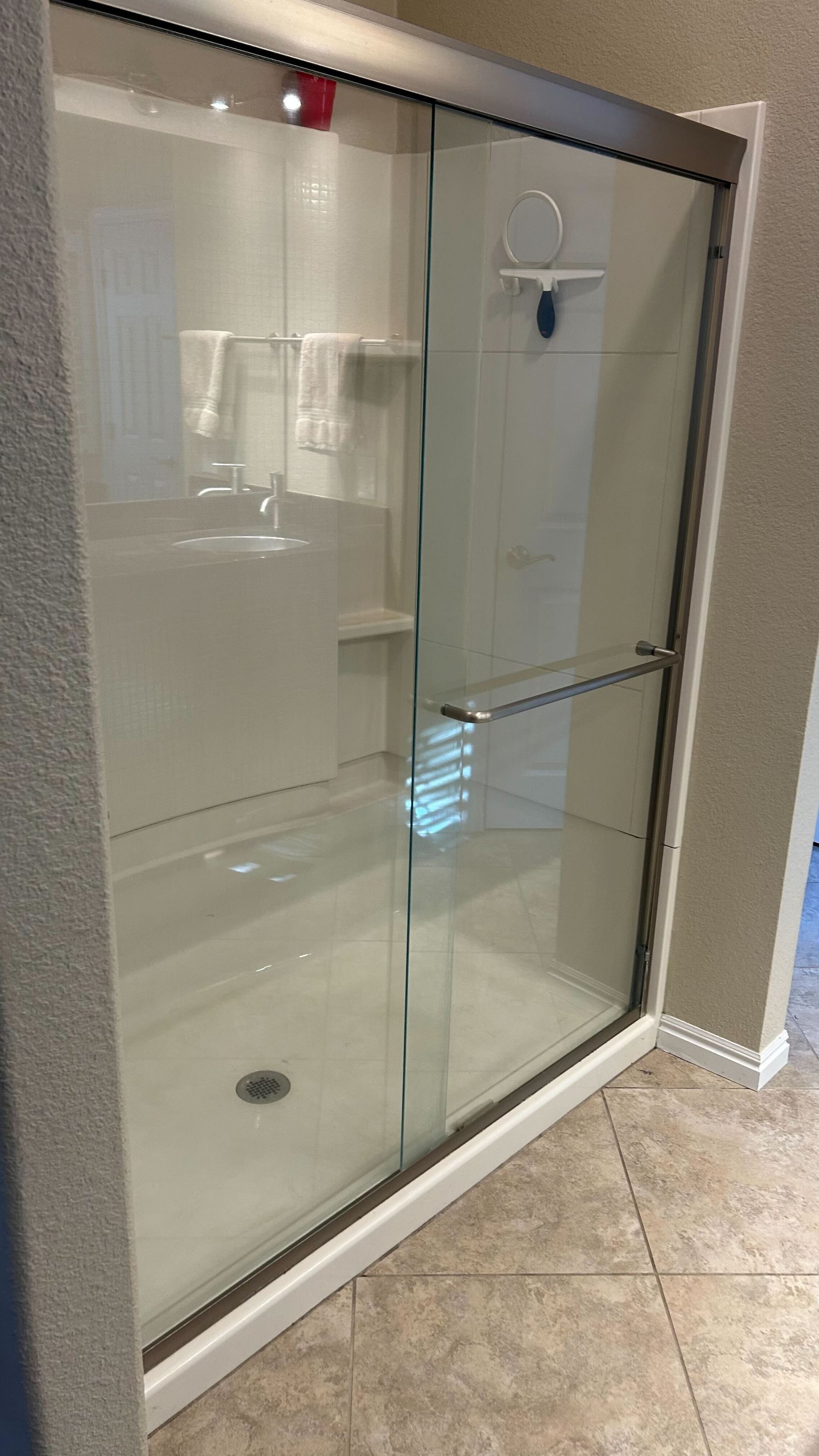 A shower stall with sliding glass doors in a bathroom.