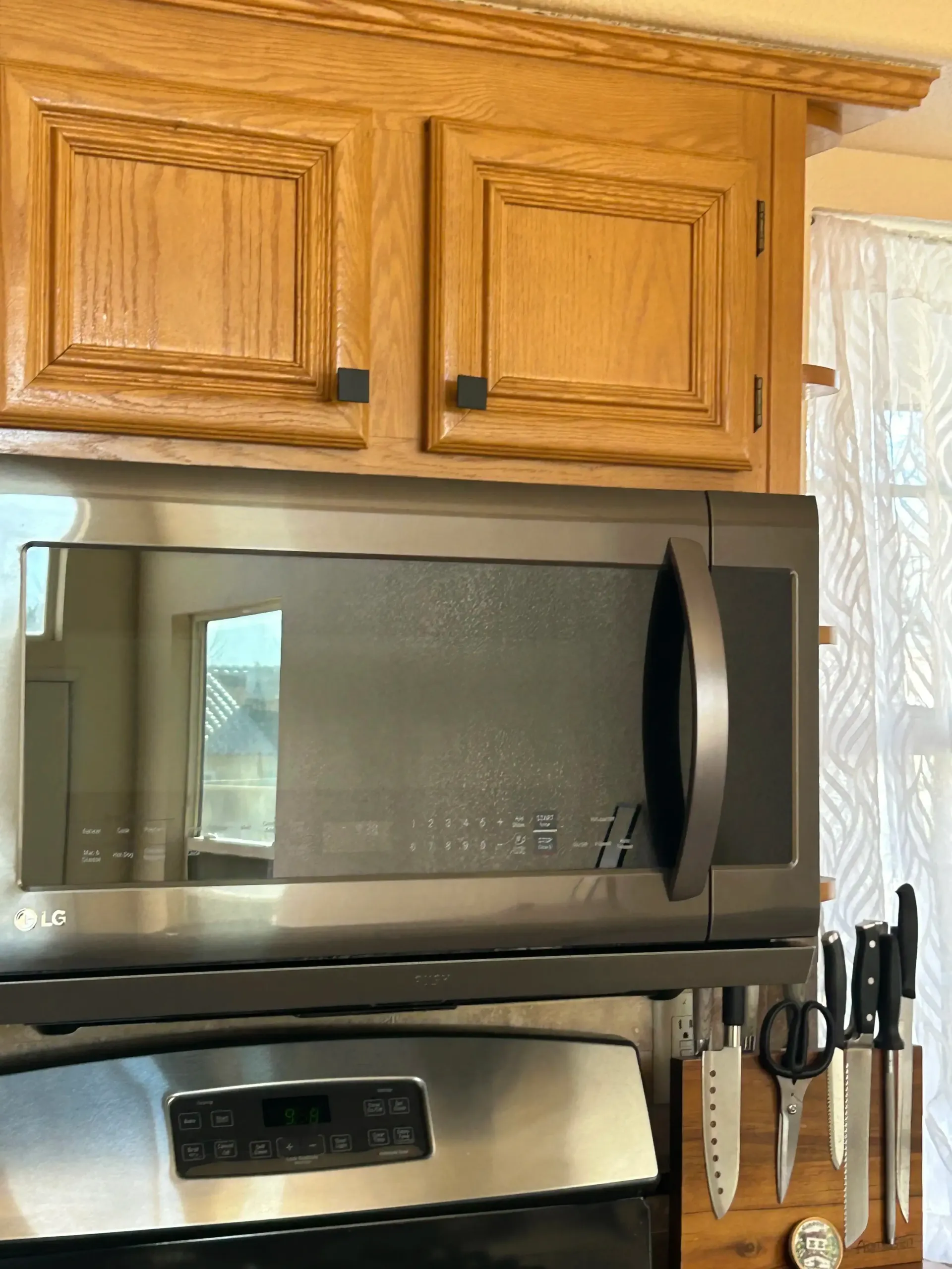 A stainless steel microwave is above a stove in a kitchen