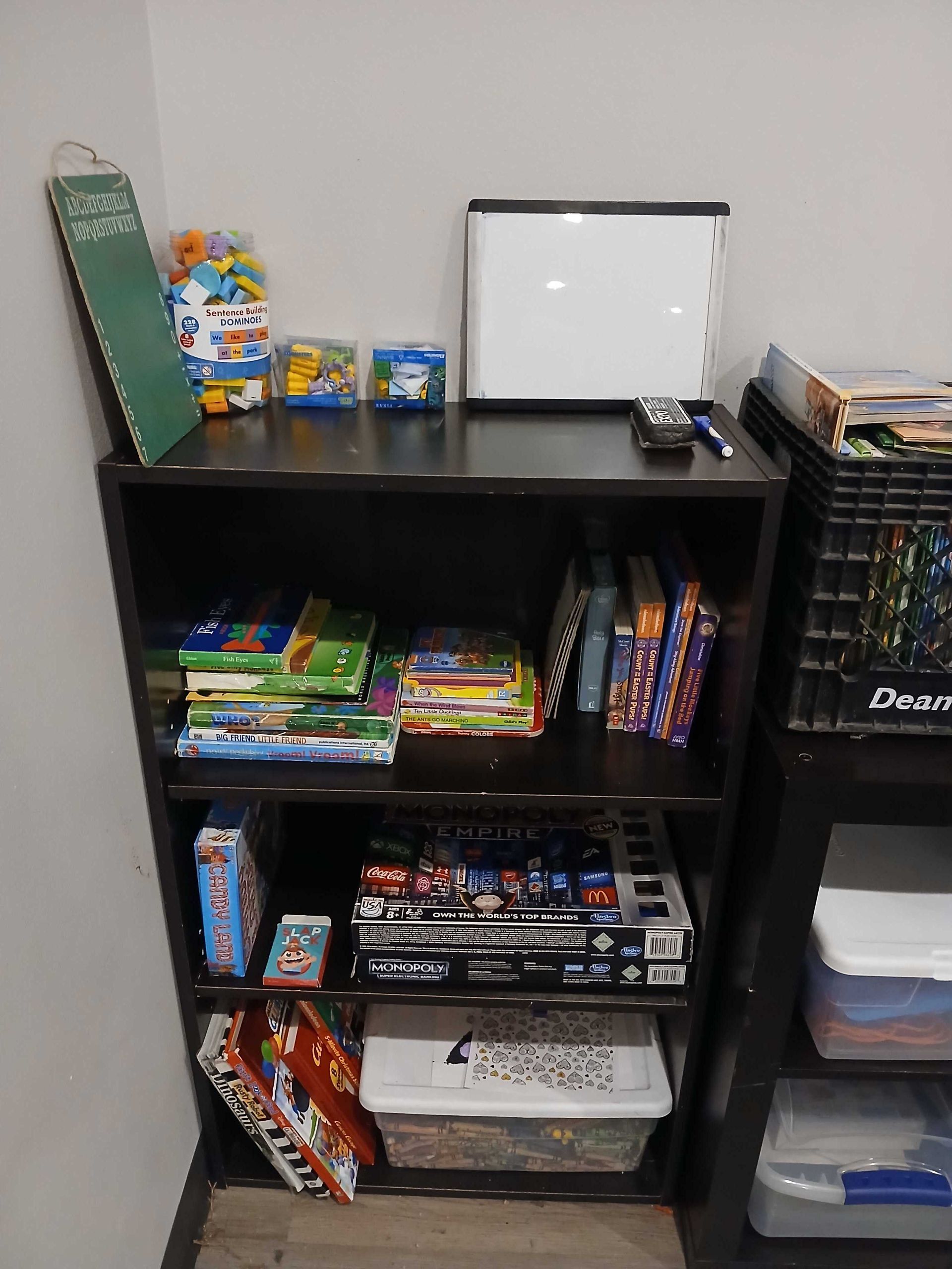 A shelf filled with books and toys in a room.