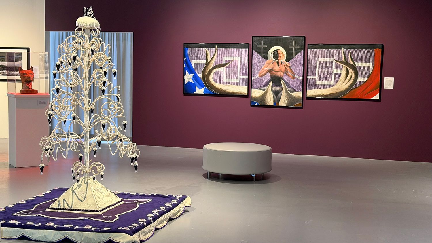 Art gallery room with a tall crystal sculpture on a purple rug and framed abstract paintings on a purple wall