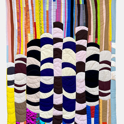A quilt with vertical multicolored stripes above a central motif of bold, repeating black and white curved shapes.