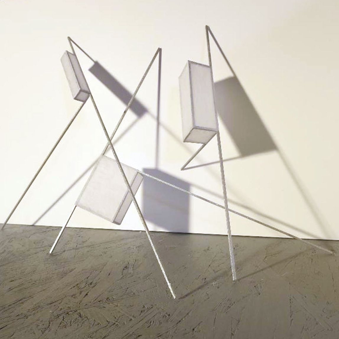 Abstract wire sculpture with white panels and long shadows on a textured floor against a light wall