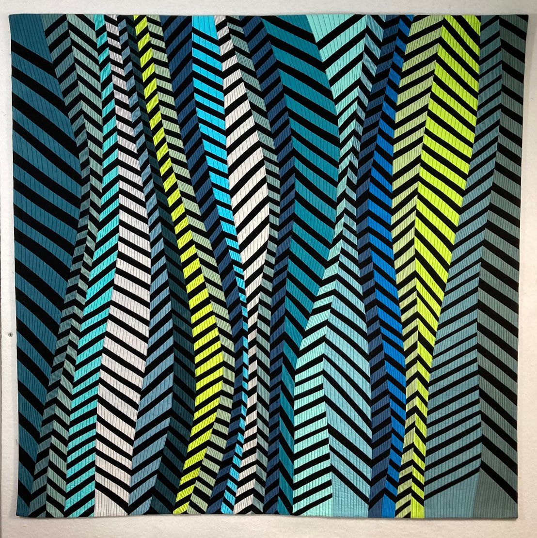 Collage quilt with three black-and-white portraits on a multicolored patterned background made up of seed bags