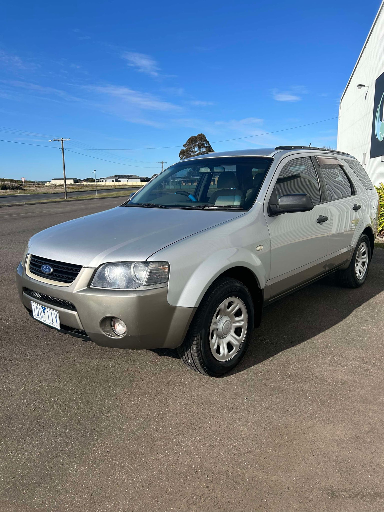 A silver ford escape is parked in a parking lot.