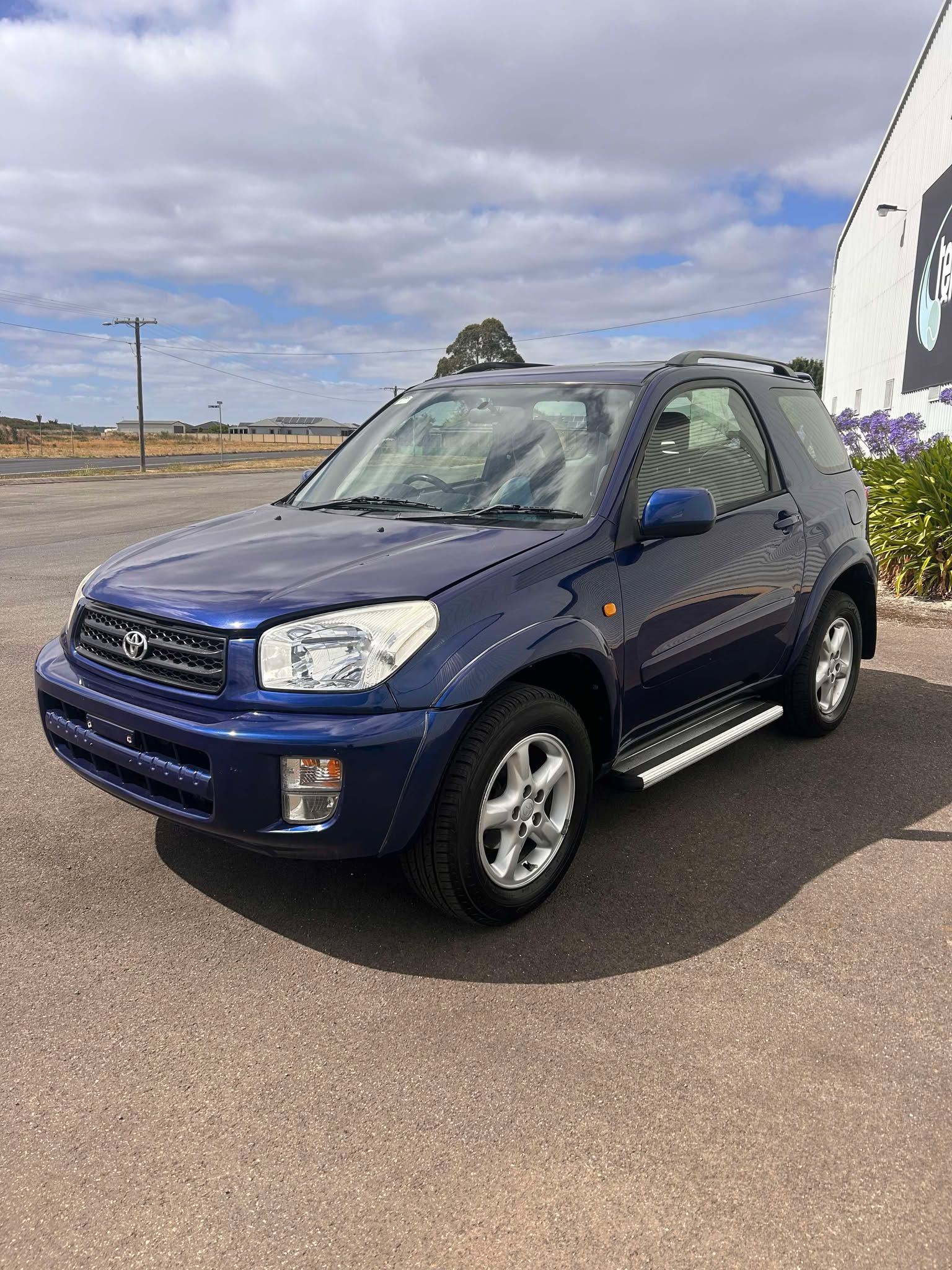 A blue toyota rav4 is parked in a parking lot.
