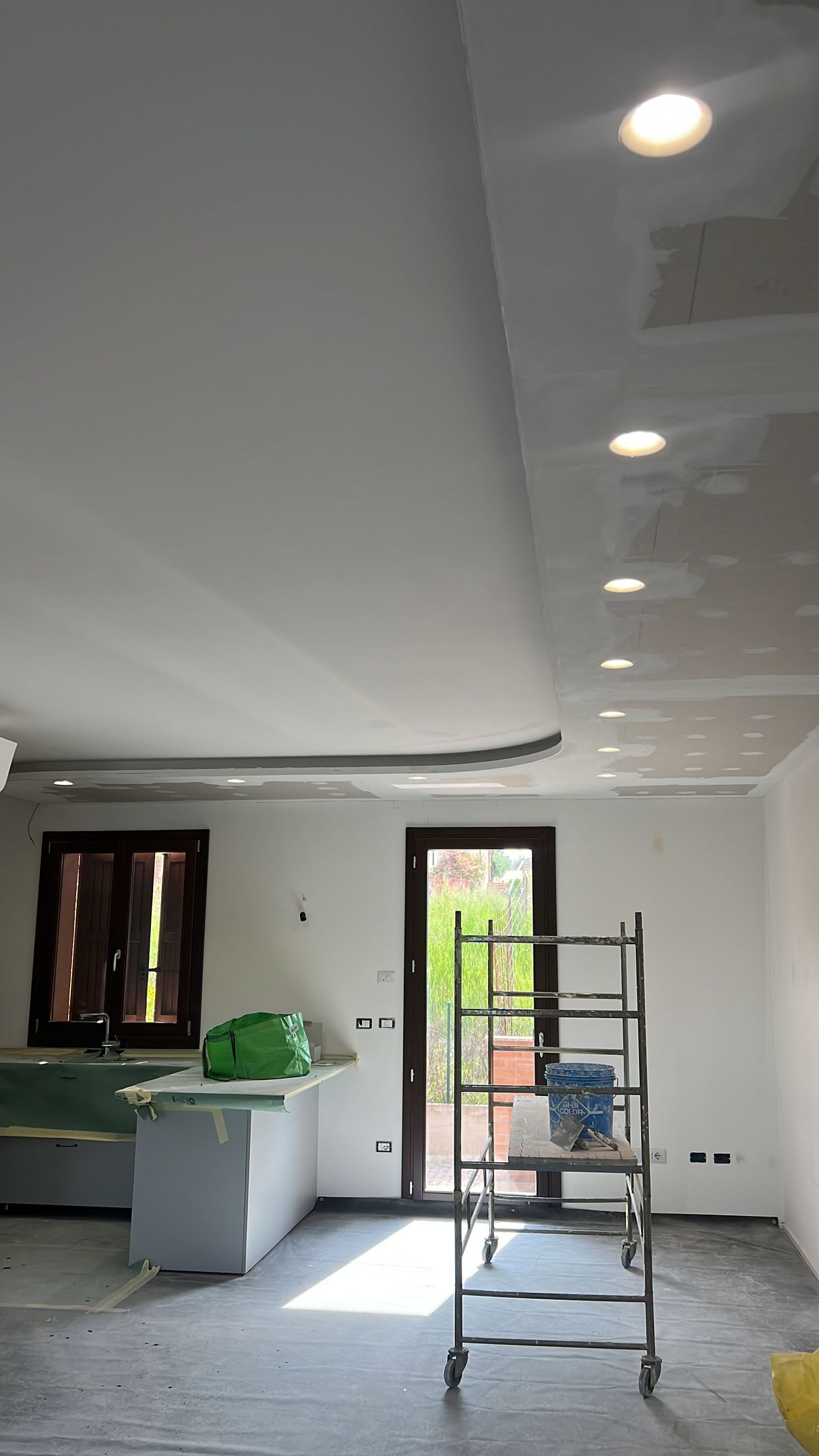 Lavori di ristrutturazione interni in corso, cartongesso e illuminazione da incasso. Impalcatura davanti a una porta.