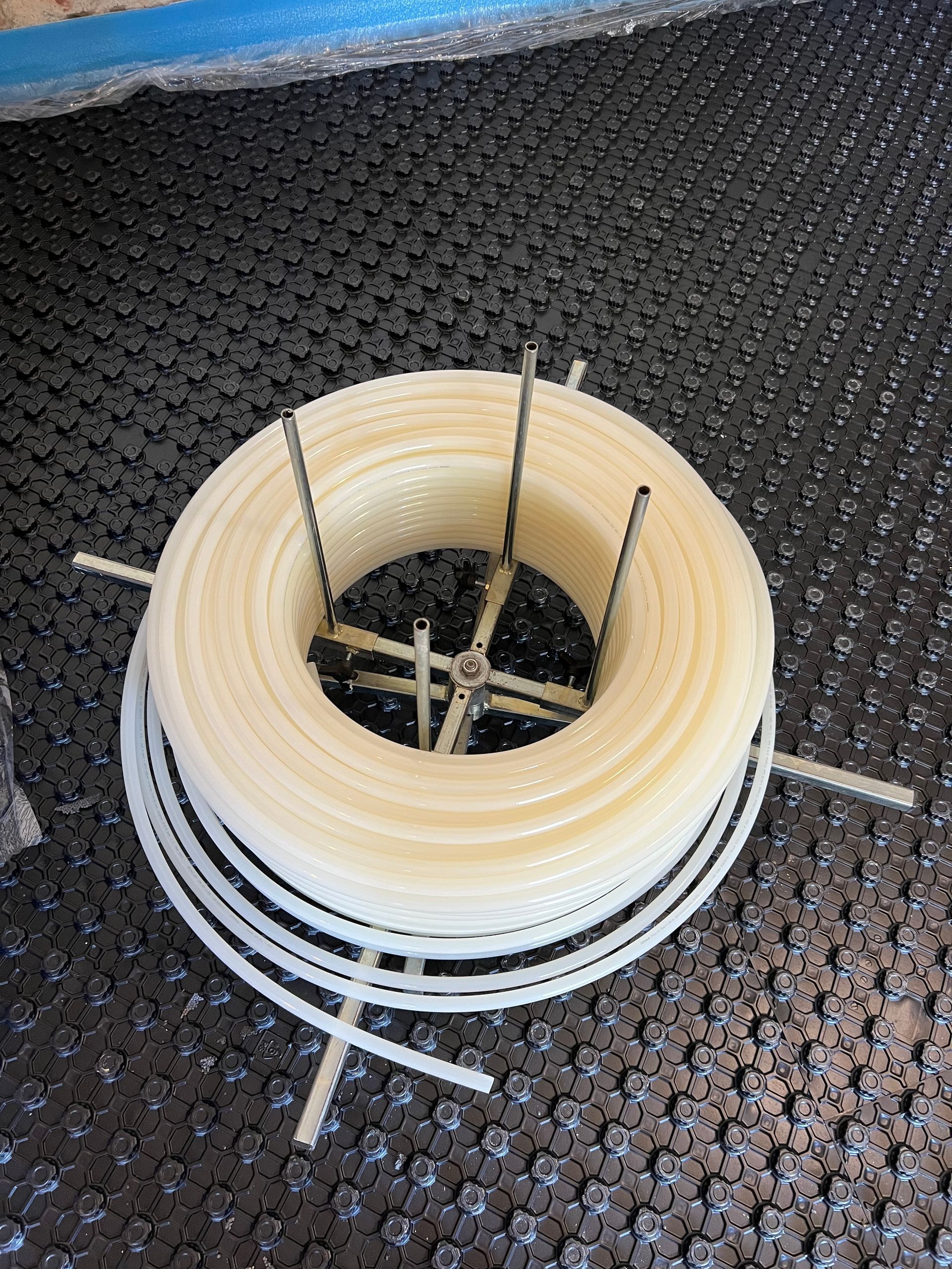 Tubo bianco arrotolato, sostenuto da un supporto metallico e appoggiato su una superficie scura decorata.