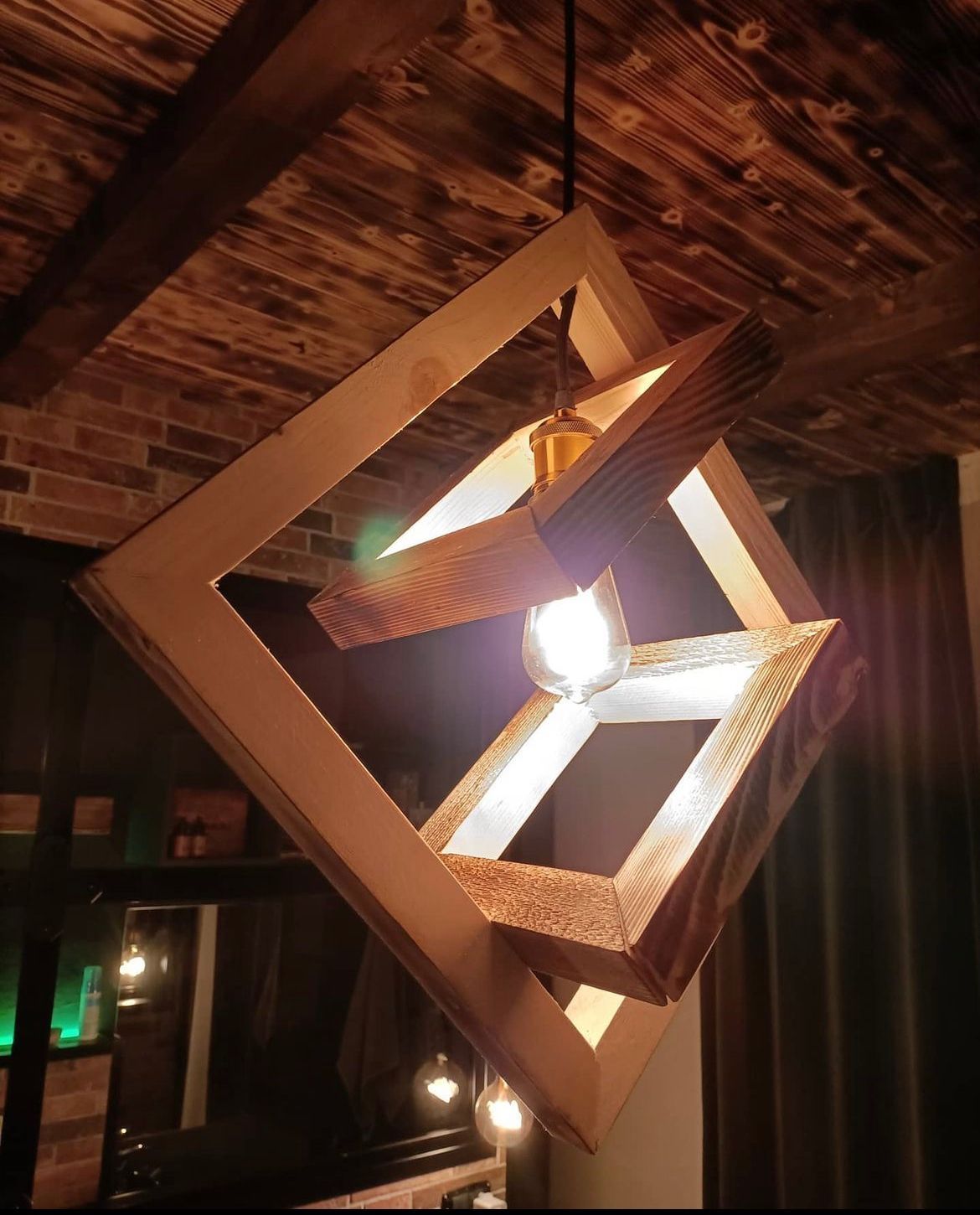 Lampadario geometrico in legno con lampadina a vista, appeso al soffitto.