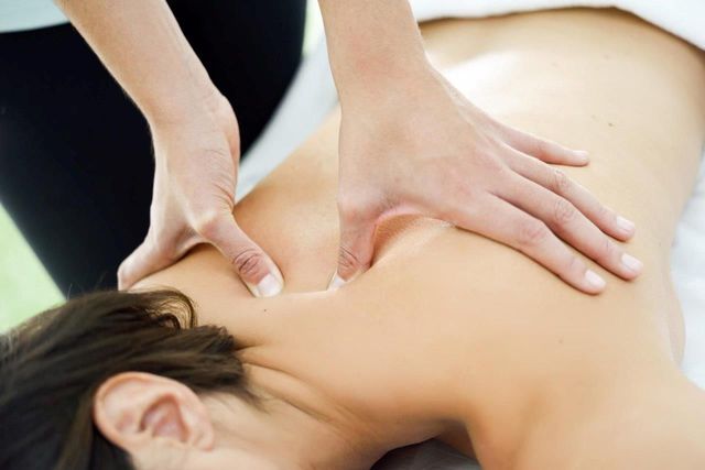 Mani che massaggiano le spalle di una persona in una spa.