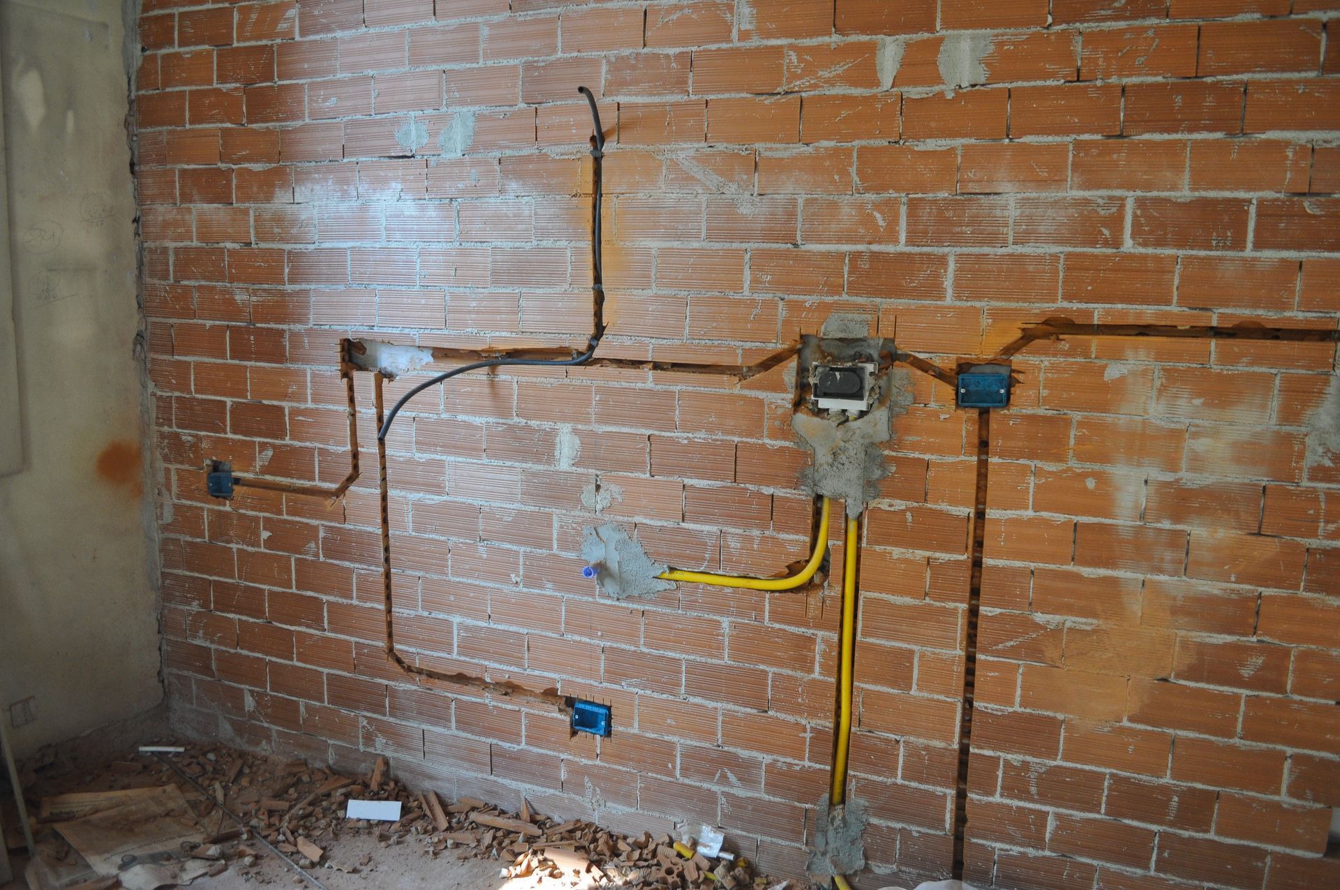 A brick wall with a bunch of wires coming out of it