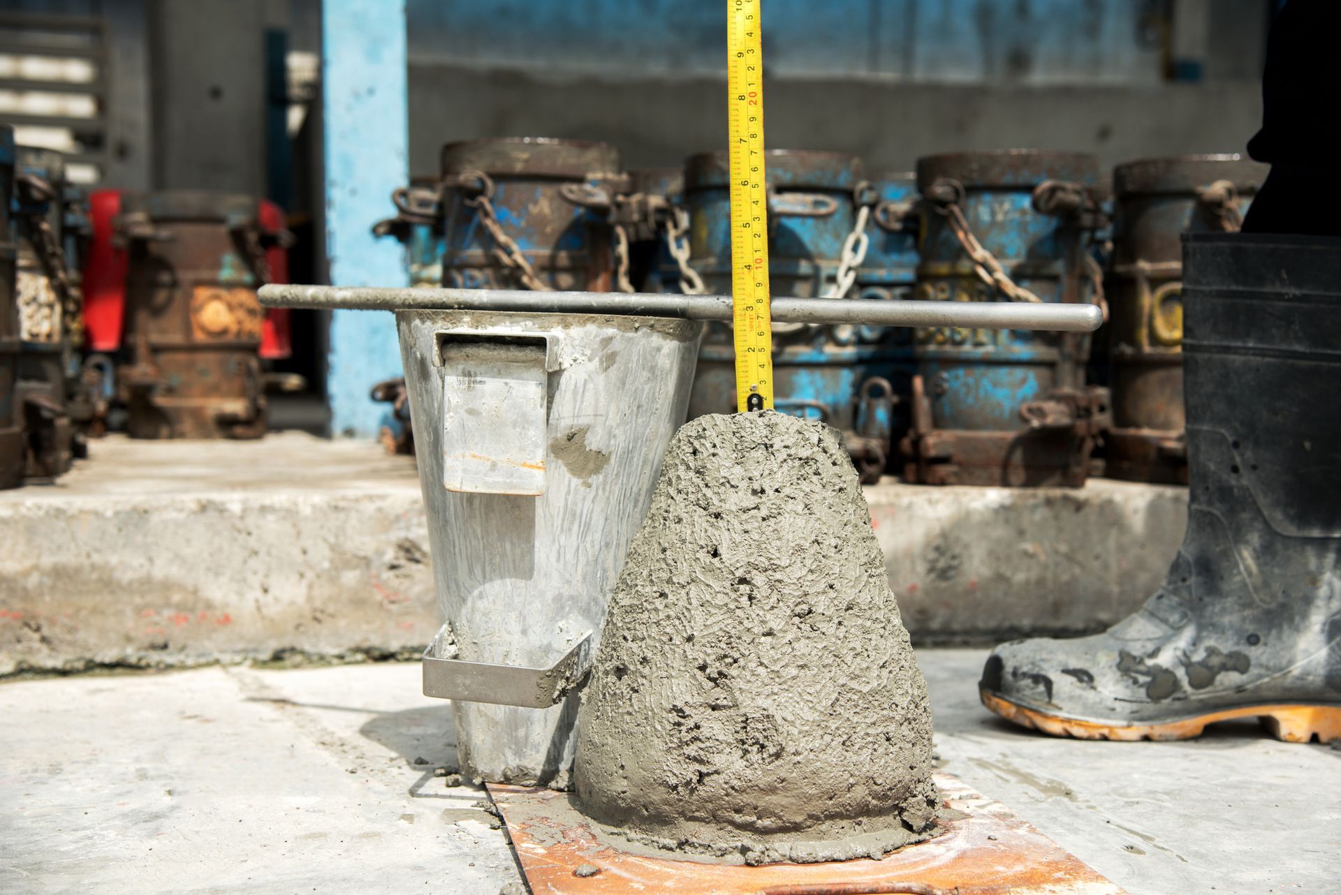 A person is measuring a pile of concrete with a tape measure.