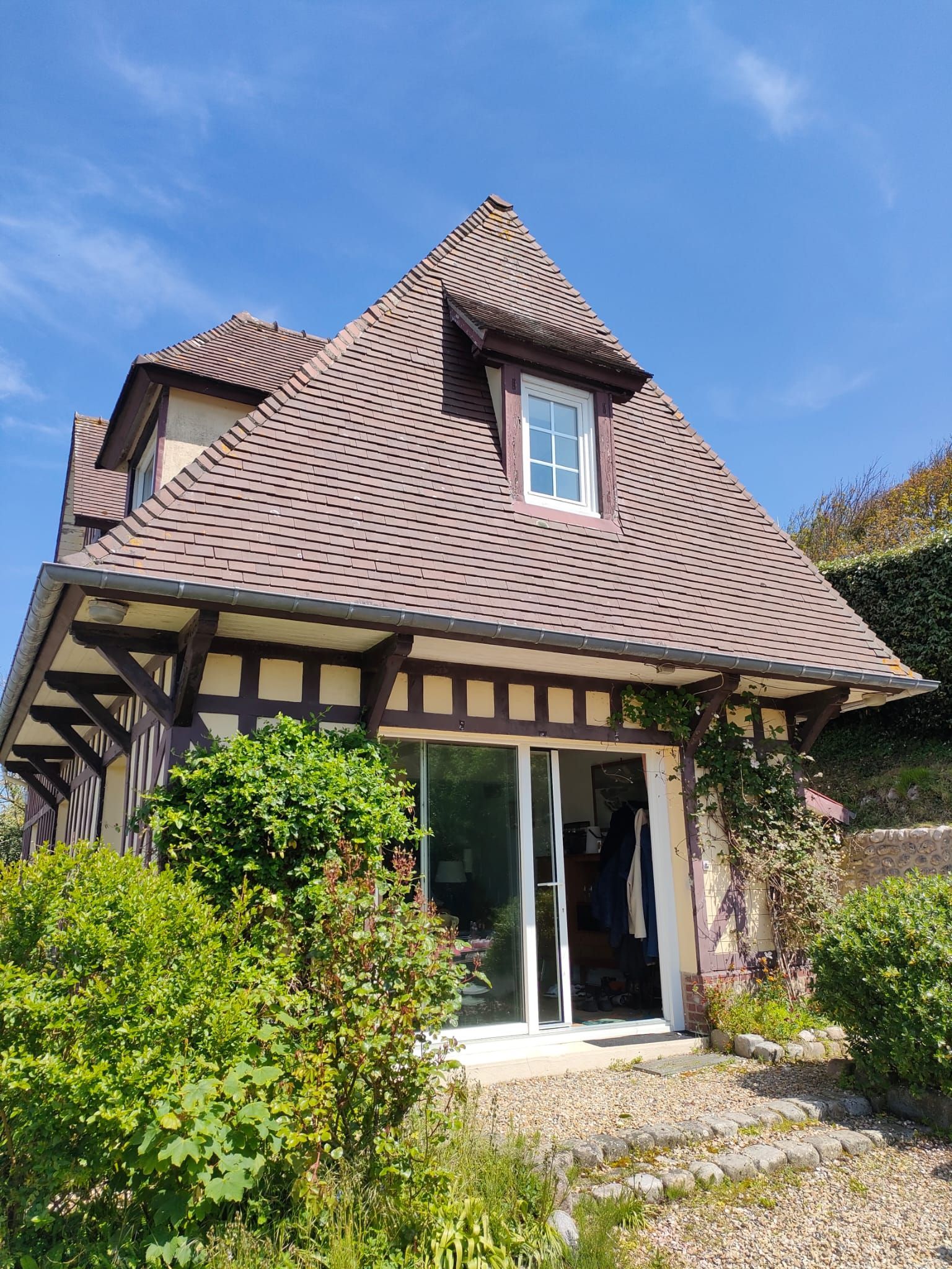 Charmant cottage à colombages, avec un toit de tuiles brunes et des portes coulissantes en verre
