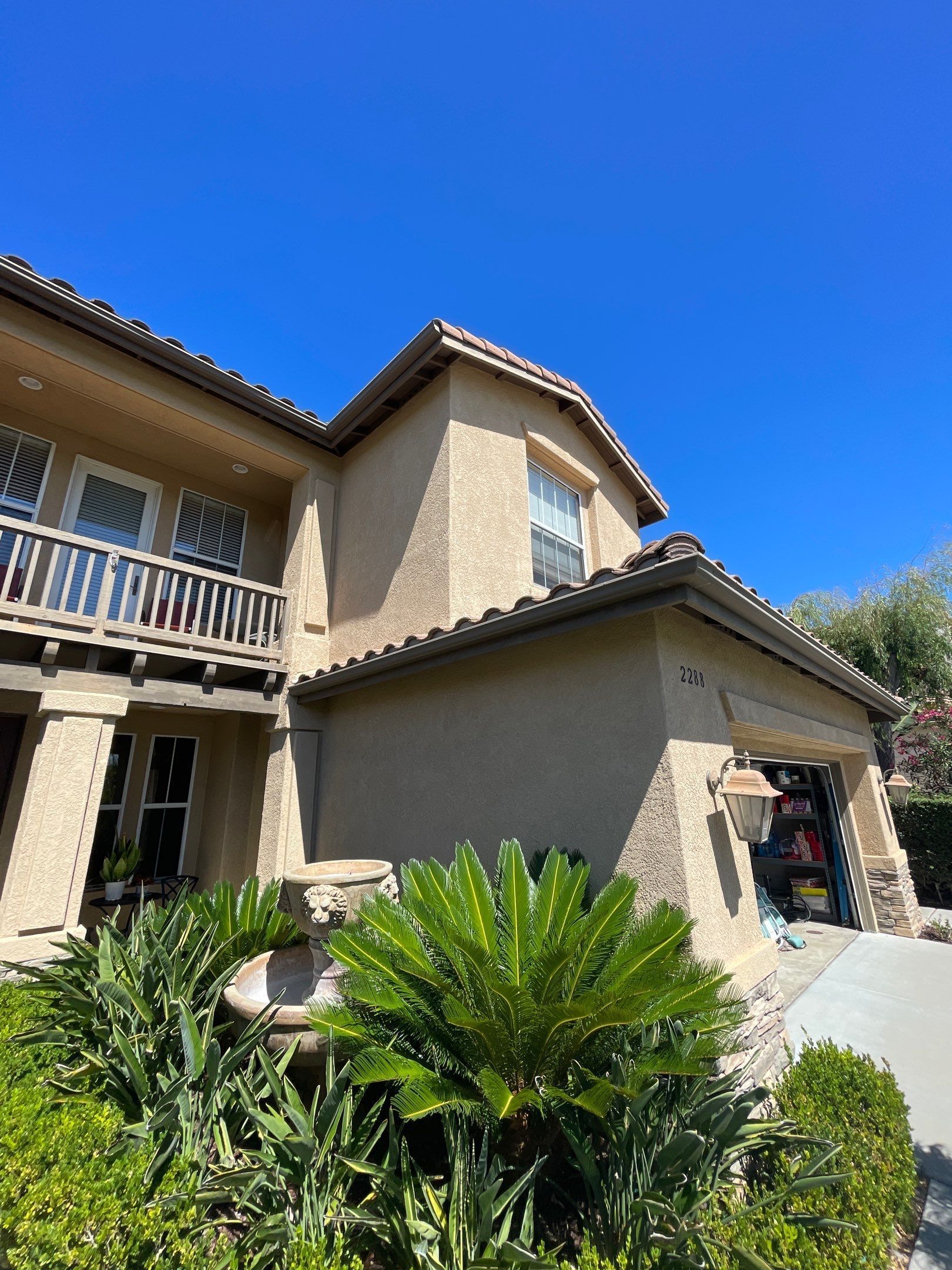 Exterior view of a stucco house with a tile roof and a swimming pool.