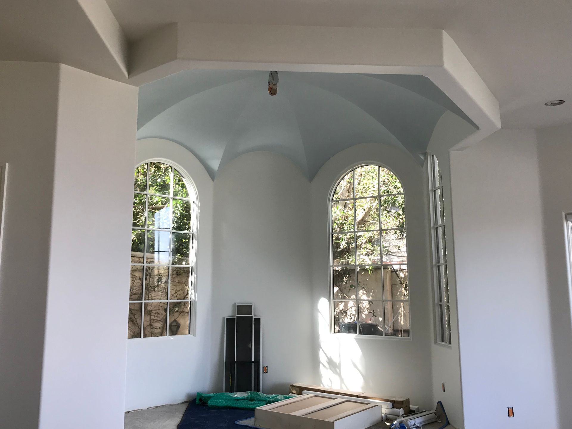 Interior with arched windows, light blue vaulted ceiling, and white walls.