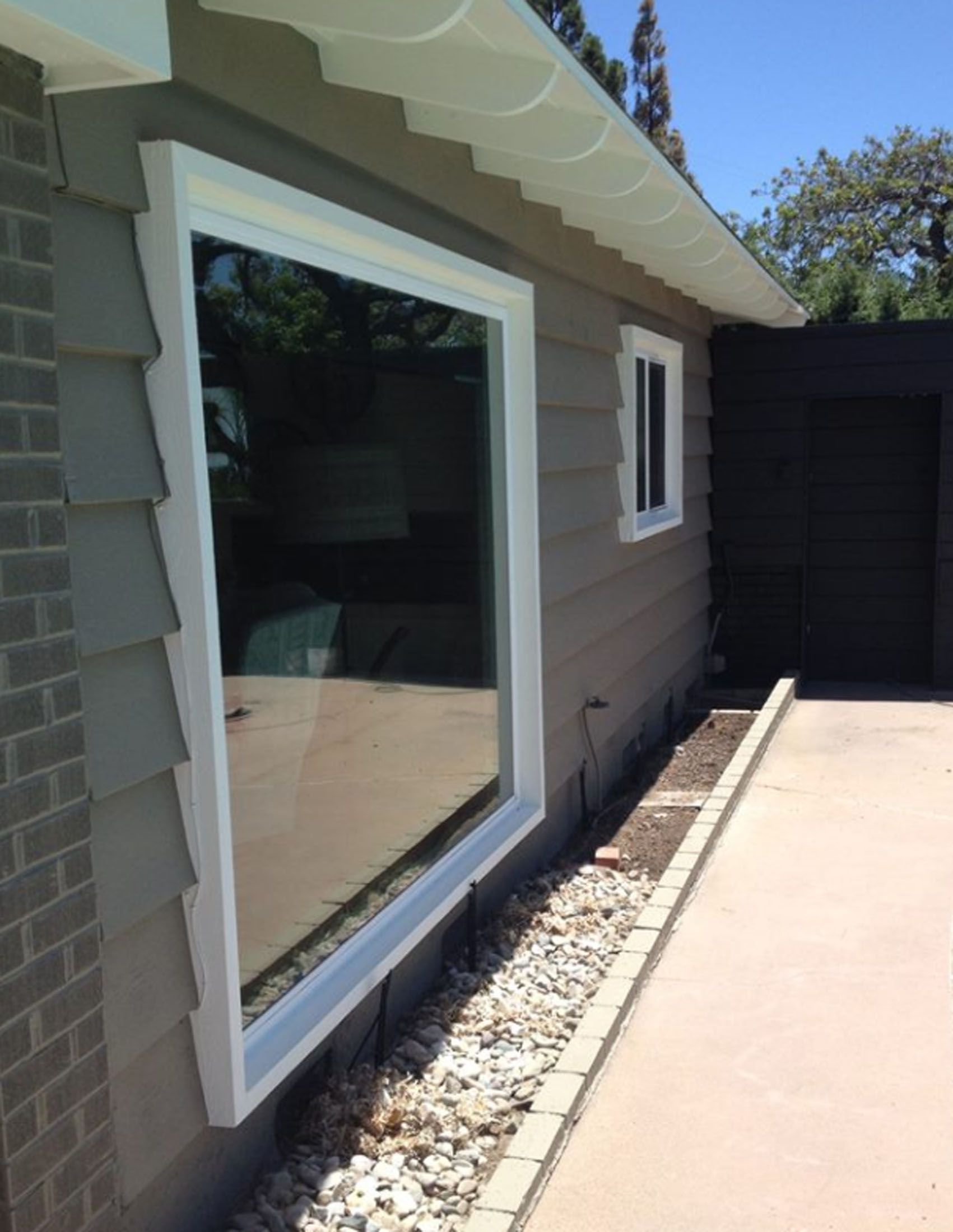 Large window with white trim on a house with gray siding.