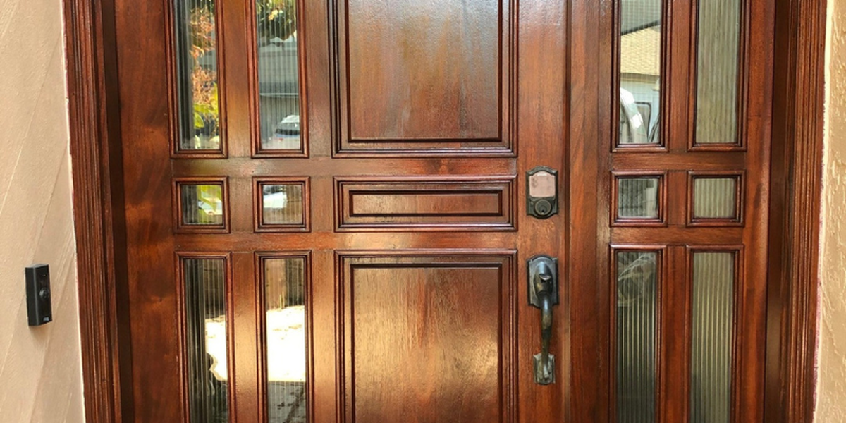 Brown wooden front door with glass panels and a digital lock.