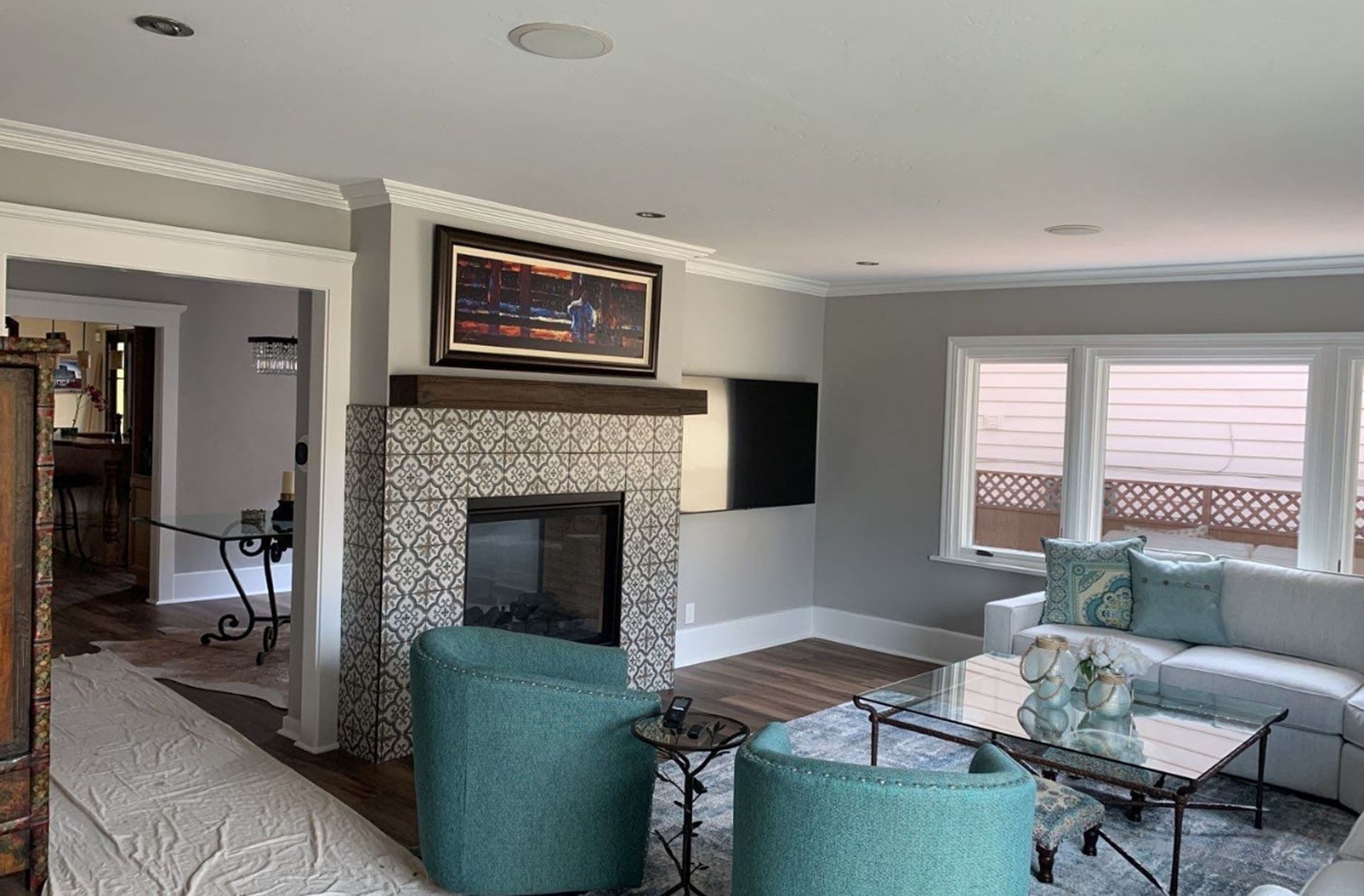 Living room with a fireplace, teal chairs, a white sofa, and a painting above the fireplace.