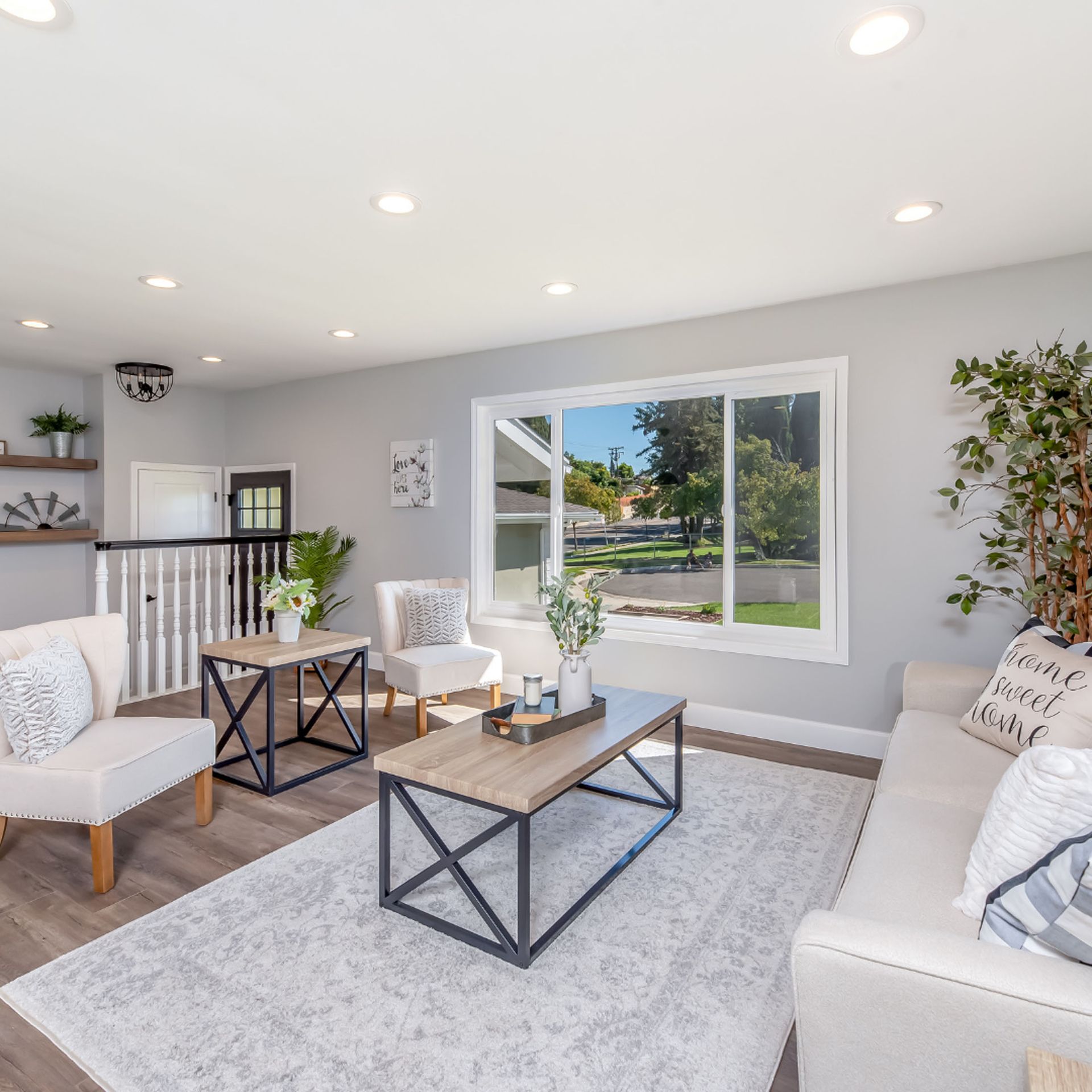 Bright, modern living room with neutral colors, a large window, white furniture, and a rug.