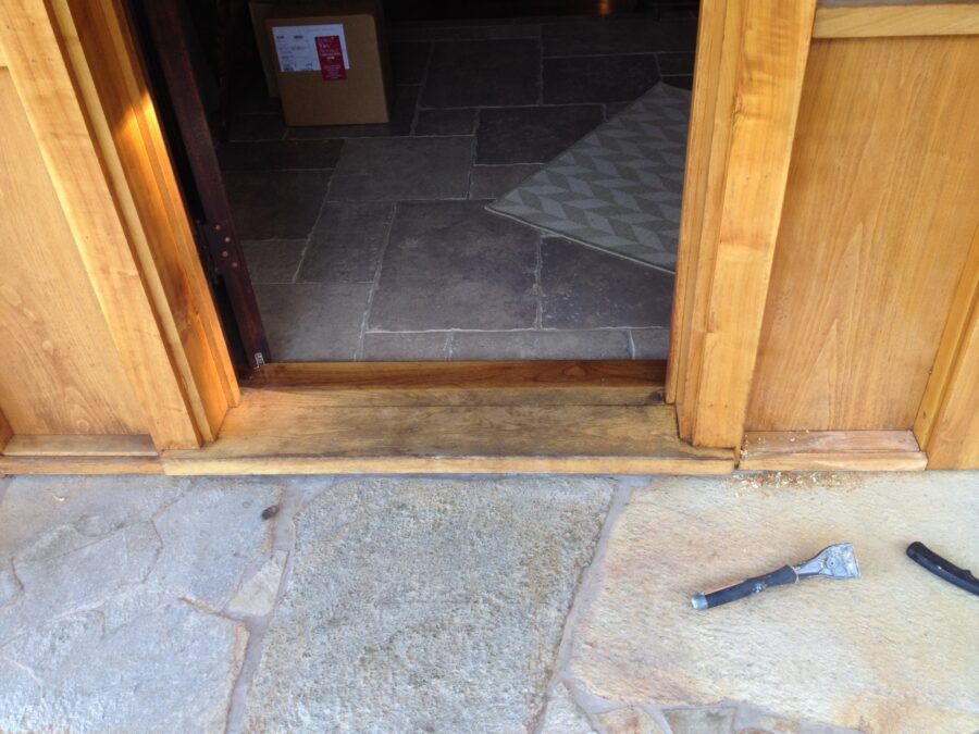 Wooden door frame with a threshold. Stone floor and an open doorway.