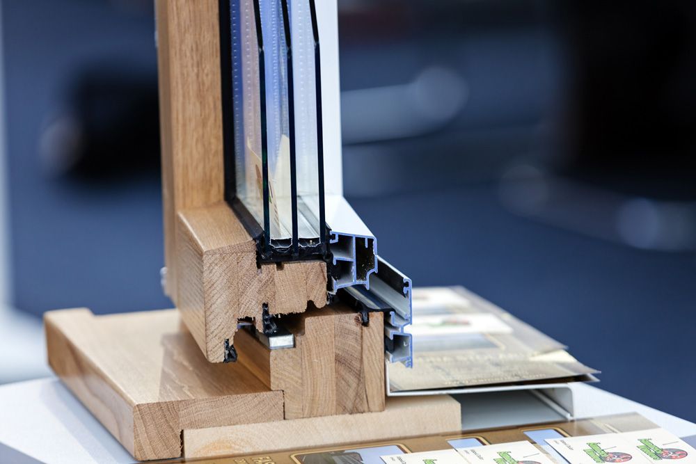 Cutaway view of a wooden window frame showcasing multiple glass panes and insulation layers.