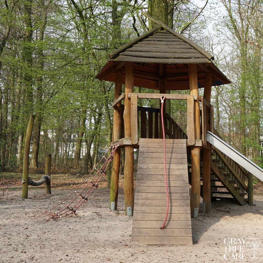 Wooden playground tower with a slide and stairs in a wooded park