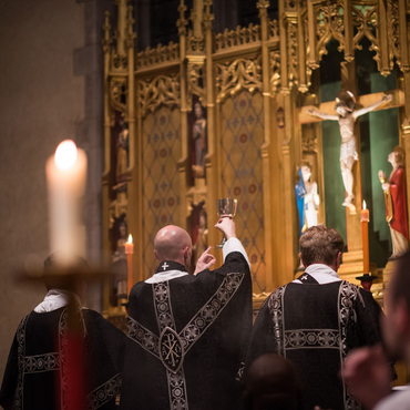 A religious procession with altar servers carrying candles and incense at an altar, in church.