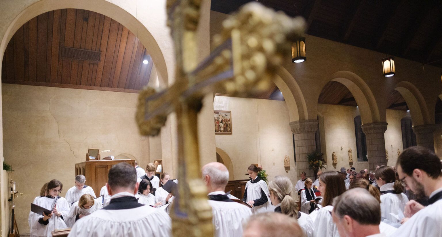A group of people are standing in a church holding a cross.