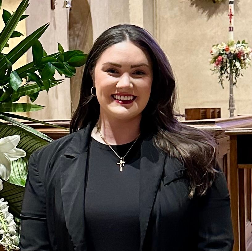 Woman with dark hair, wearing a blazer, smiling.