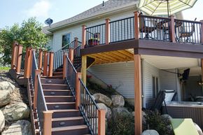 Wooden staircase leading to a raised deck and house amid rocks and greenery
