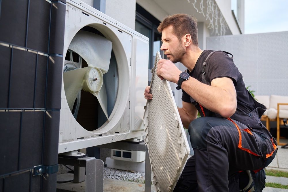 Technician inspecting outdoor HVAC unit with a flashlight and tools
