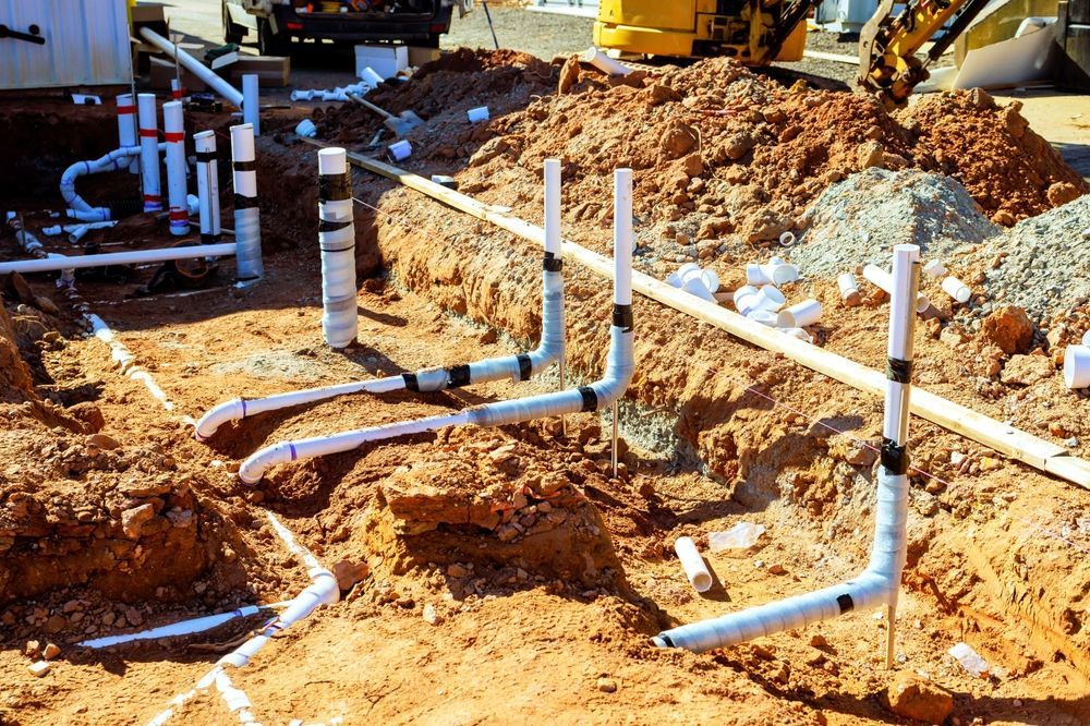 Construction site with exposed white PVC pipes and dirt trenches