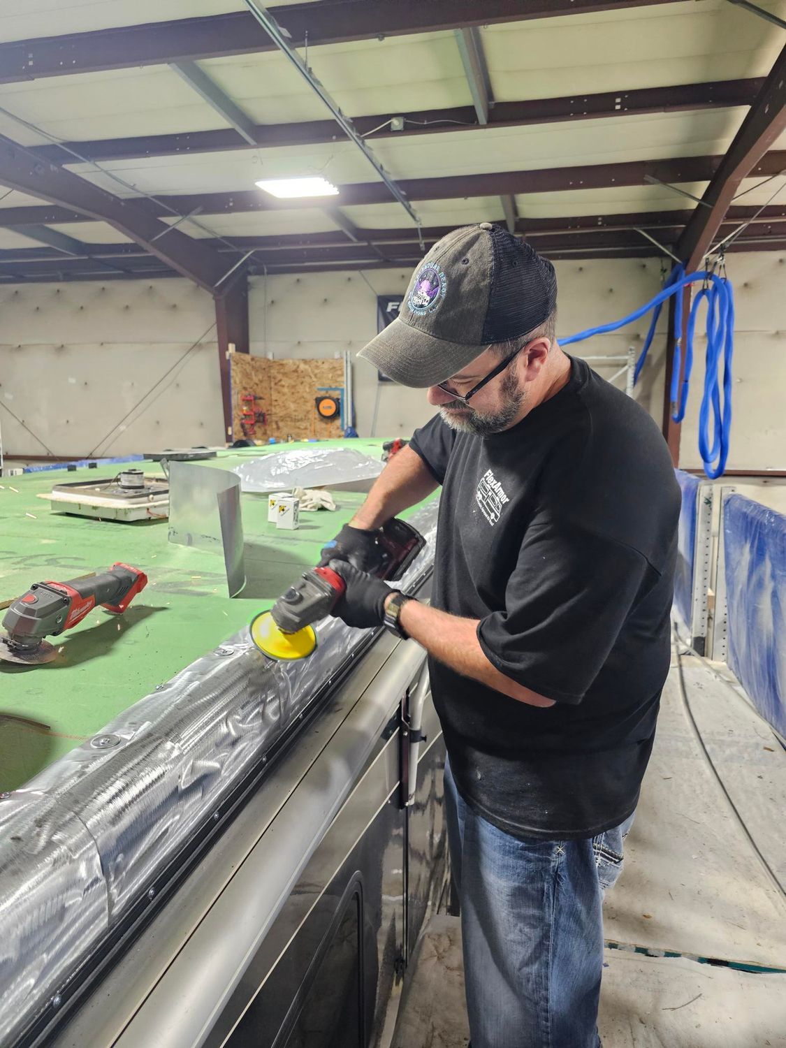 A person using a power tool to polish a metal surface in a workshop.