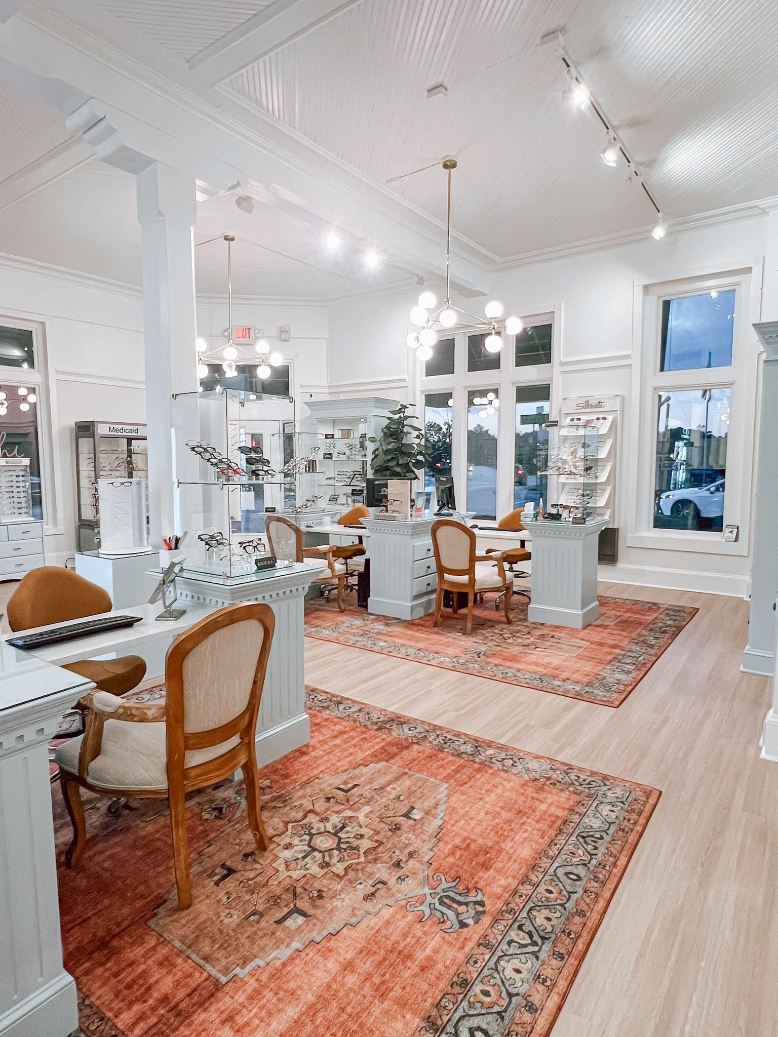 Bright white dining room with patterned rugs, wooden chairs, and large windows overlooking a garden in Hope Mills, NC.