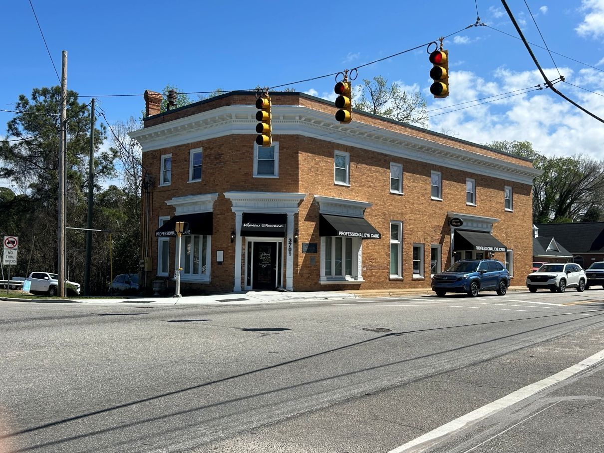 Brick corner building with storefronts at a street intersection under hanging traffic lights near Fayetteville, NC.
