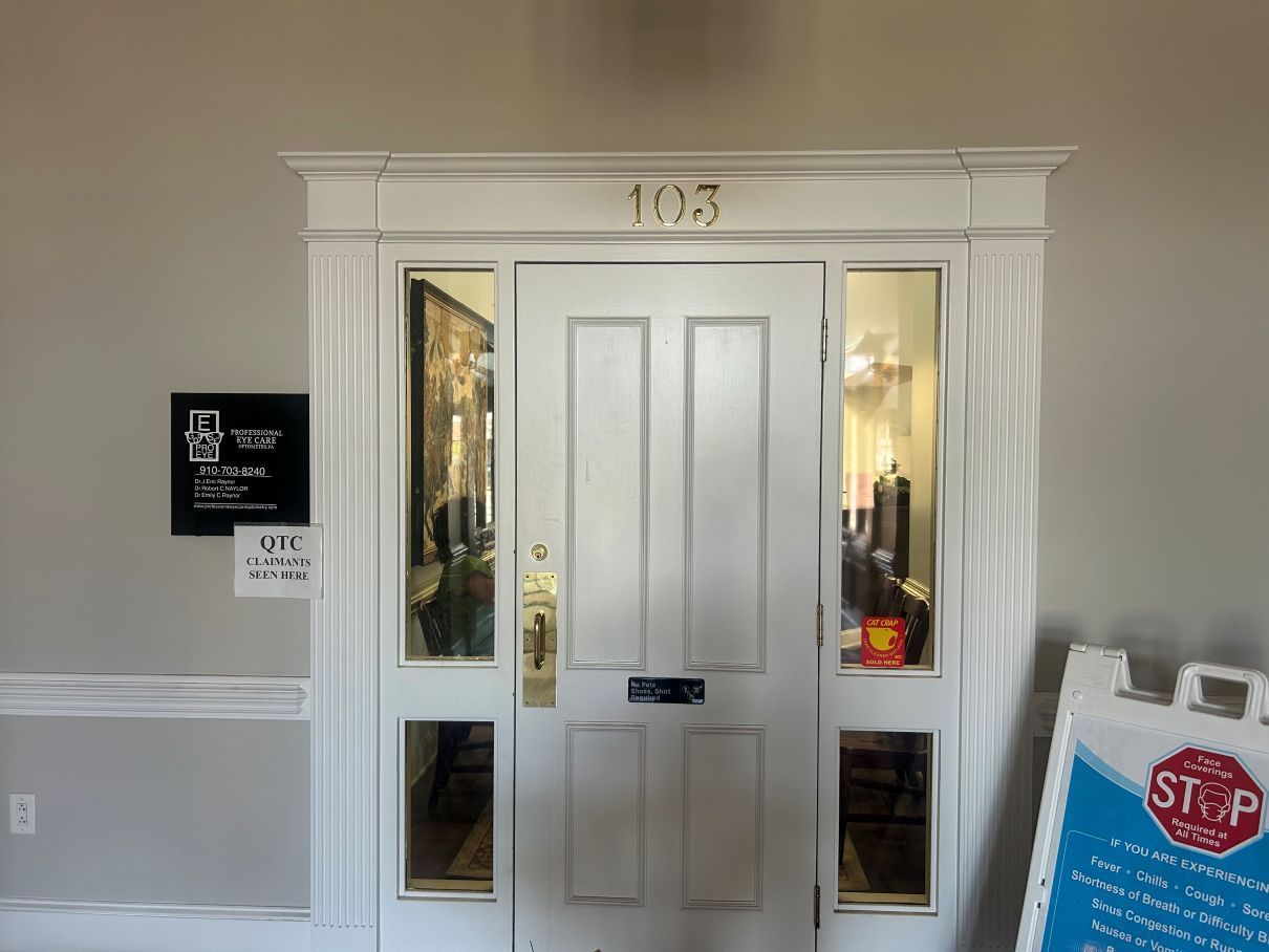 White building entrance with a door, sidelights, and a stop sign on an A-frame by the doorway in Eastover, NC.