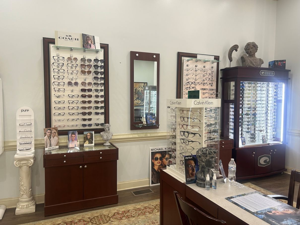 Eyeglass display room with multiple frames on wall stands and cabinets, plus a central mirror stand in Eastover, NC.
