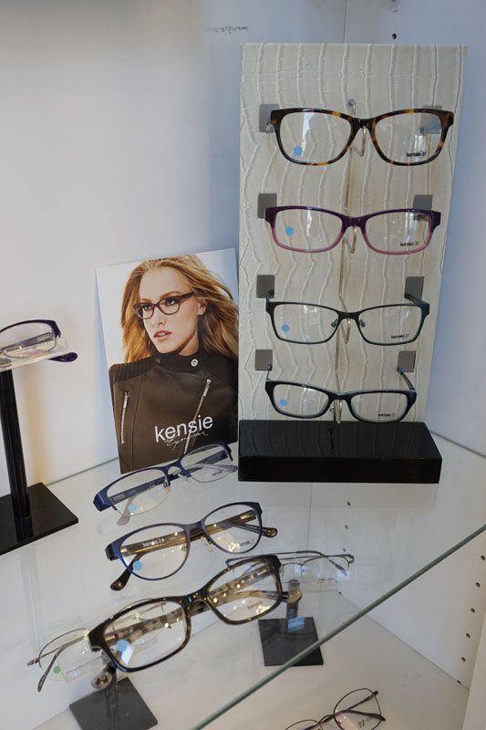 Eyeglass display with several pairs of glasses on stands and a model photo in a store in Hope Mills, NC.