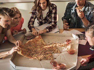 Un gruppo di persone sedute attorno a un tavolo condivide una grande pizza da