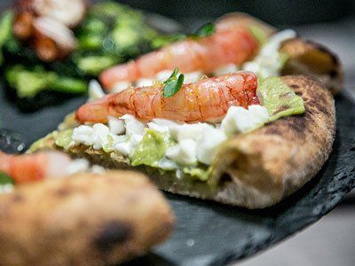 Primo piano di una fetta di pizza condita con gamberetti cotti