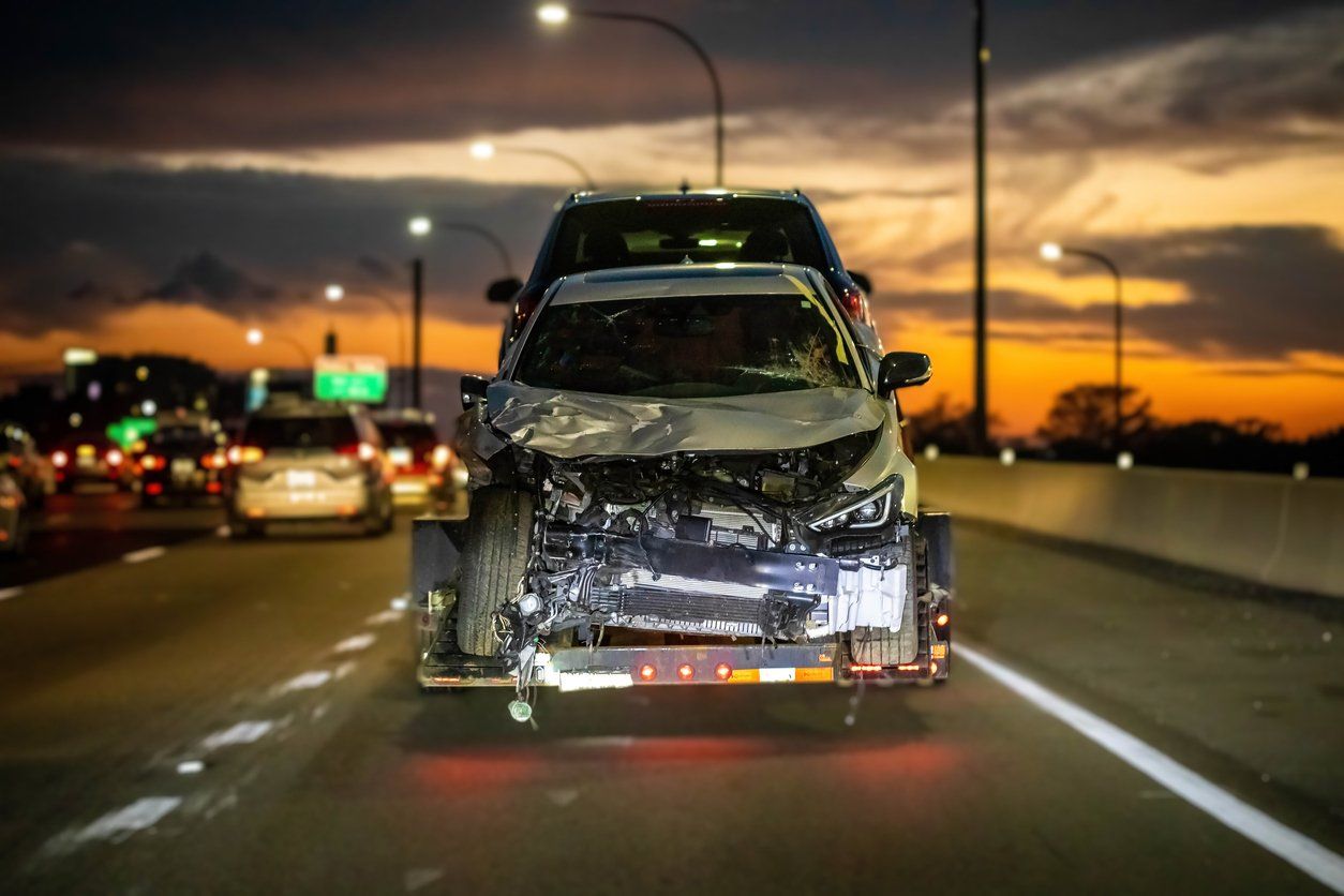 A damaged car is driving down a highway at night.