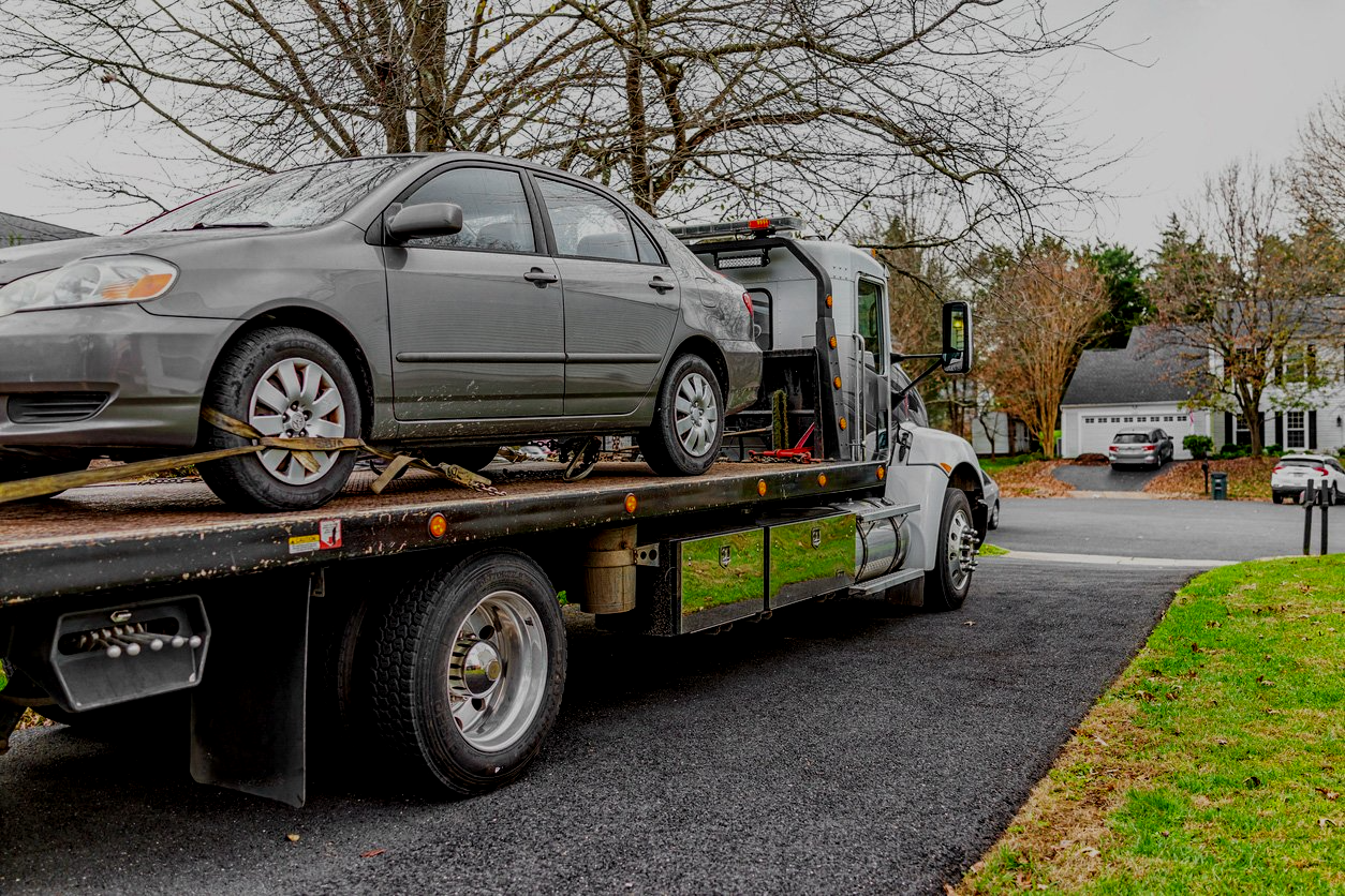 A tow truck is carrying a car on the back of it.