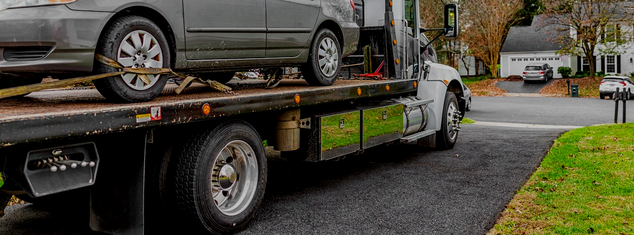 A tow truck is carrying a car on the back of it.