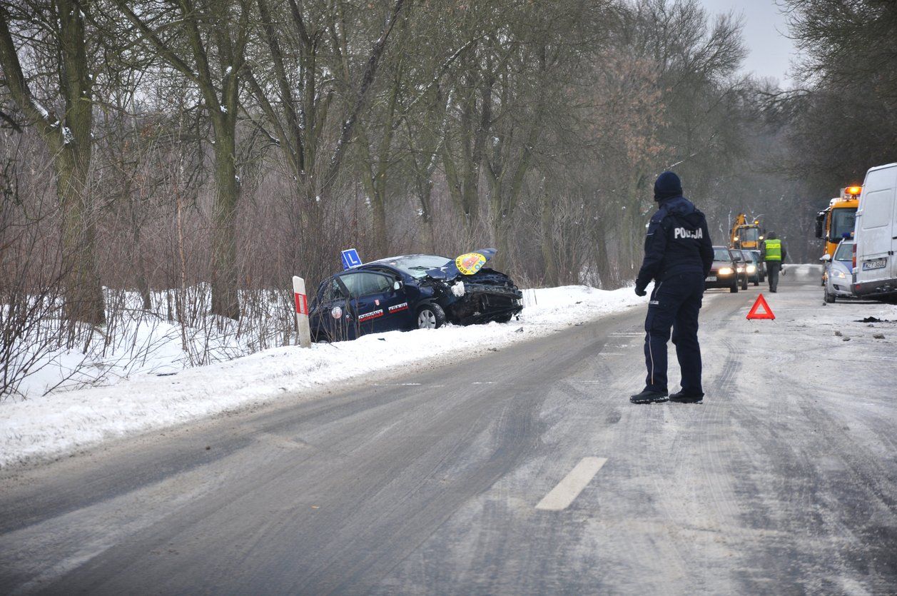 A man is standing on the side of a snow covered road.
