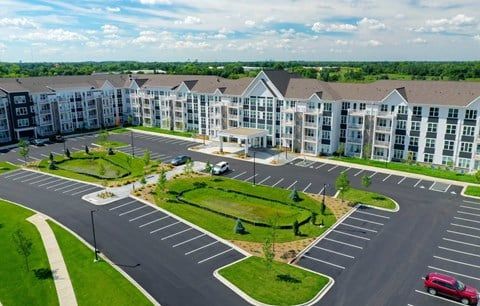 An aerial view of a large apartment building with a parking lot in front of it.