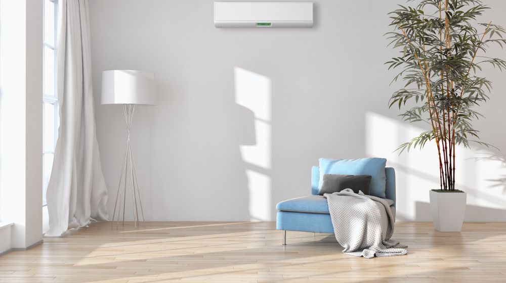A Living Room with a Blue Chair, a plant, a Lamp and an air Conditioner — Hunter Valley Tile Mart in Rutherford, NSW