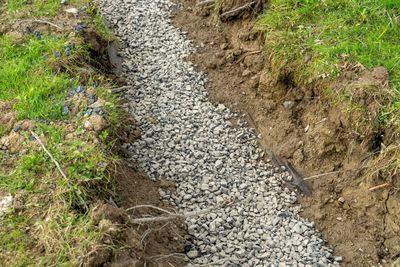 Gravel path cutting through a dirt trench with grass on both sides